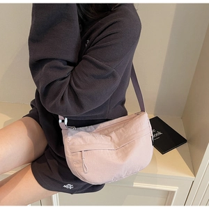 Detail view of the pale pink nylon crescent crossbody bag with adjustable wide shoulder strap