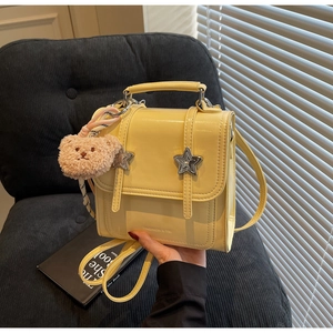 Detail of yellow mini backpack with metal star buckles and brown plush bear charm