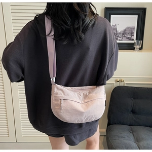 Close-up of light purple nylon crossbody bag featuring textured fabric and adjustable strap