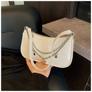 Detailed shot of white patent leather baguette bag with silver chains and heart charm