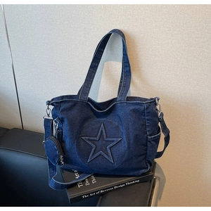 Vue détaillée d'un sac cabas en denim bleu foncé avec étoile en relief et petit porte-monnaie