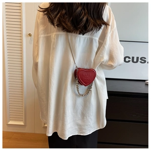 Detail of red heart-shaped mini crossbody bag with silver bead chain and metal strap