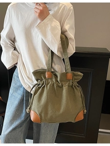 Olive green canvas tote bag with brown leather patches and drawstring closure
