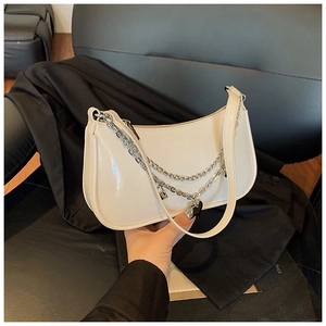 Detail of cream white faux leather hobo bag with silver chain and black heart pendant