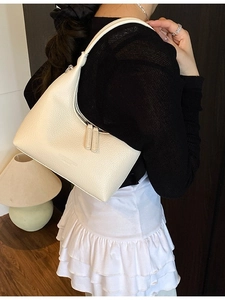 Elegante borsa sottobraccio in pelle color crema con motivo litchi su modella
