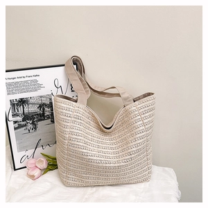 Close-up of natural woven tote bag texture with fabric shoulder straps in soft indoor light