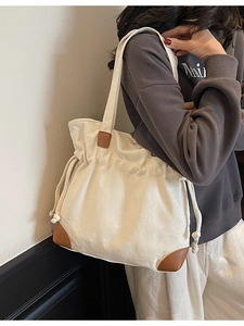 Minimalist beige canvas tote bag with brown faux leather trim and drawstring closure