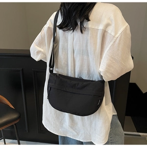 Detail view of a black lightweight nylon crescent bag with adjustable strap and logo label