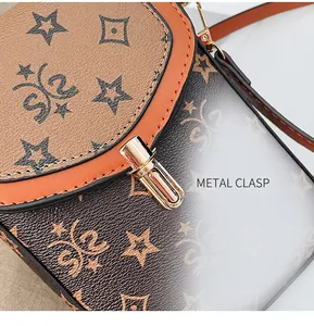 Detailed macro shot of the golden metal twist-lock on a brown star-patterned crossbody bag