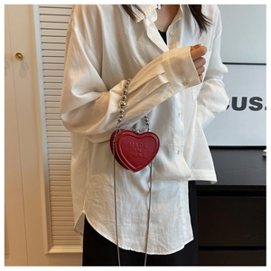 Detail of red heart-shaped mini leather bag with silver bead chain and cross-body strap