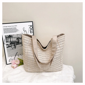 Detail of a beige woven tote bag with texture and a long fabric shoulder strap
