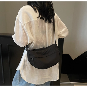 Detailed back view of a black waterproof nylon crescent crossbody bag worn by a model