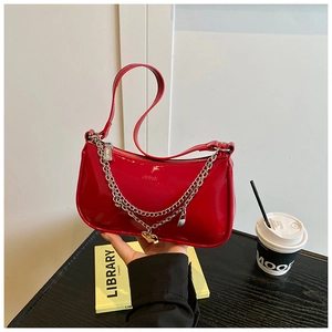 Detail of red patent leather bag with silver chain, heart charm and padlock detail