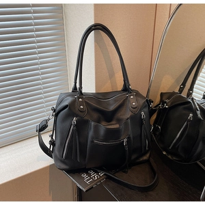 Close-up of litchi leather texture and metal zipper pockets on a black tote bag