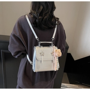 Silver metallic leather backpack with star buckles and a cute plush bear pendant