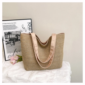 Detailed close-up of large woven straw tote bag with long fabric shoulder straps and soft lining