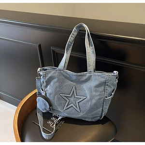 Detail of blue denim tote bag with 3D star pattern and a small round coin purse charm