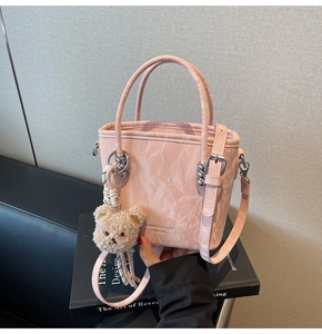 Dettaglio borsa a secchiello rosa marmorizzata con ciondolo a orsetto e finiture in argento