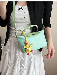 Mint green mini crossbody bag with leather flap and cute yellow duck charm on model