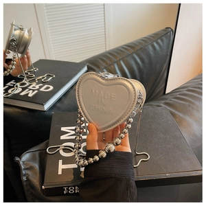 Close-up of heart-shaped silver mini bag with chunky metal bead chain and snake chain