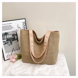 Detail of a beige woven straw tote bag on a textured white fabric with a summer vibe