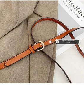 Close-up of adjustable brown leather shoulder strap with gold buckle and fine stitching