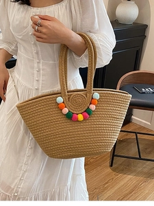 Grand sac cabas en paille kaki avec pompons colorés dans une scène de vie