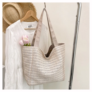 Close-up of beige woven tote bag with wide straps and textured horizontal weave patterns
