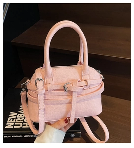 Détail d'un sac à main en cuir grainé rose avec boucles dorées et bandoulière réglable