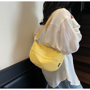 Detail of yellow nylon crescent bag with adjustable shoulder strap on female model
