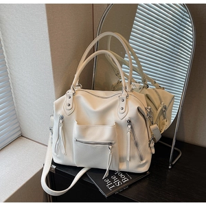 Detail of white tote bag showing soft lychee texture and silver zipper accents