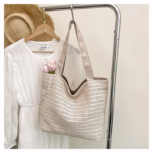 Detailed texture of beige woven straw tote bag hanging with summer outfit props