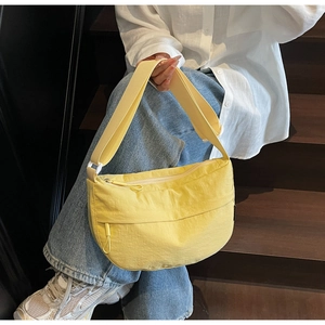 Detail of a yellow nylon crescent bag with adjustable wide strap and pleated texture