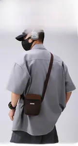 Detail of a brown crossbody phone bag with front mesh pocket and brand logo patch