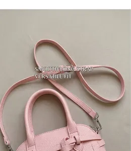 Détail du sac coquillage en cuir rose grainé avec bandoulière réglable et boucles argentées