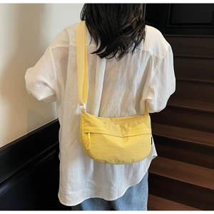 Detail view of a yellow nylon crescent bag with adjustable strap and front zipper pocket