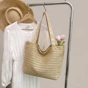 Close-up of lightweight woven straw tote bag with wide fabric handles for summer beach