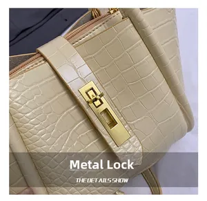 Close-up of golden metal twist lock on cream-colored crocodile embossed bucket bag