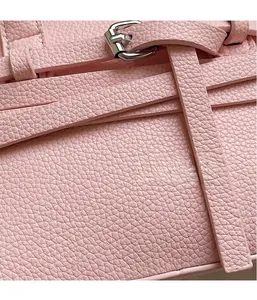 Gros plan du cuir grainé rose cerise et boucle argentée d'un sac à main élégant
