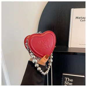 Detail of red heart mini bag featuring large silver bead handle and metal chain