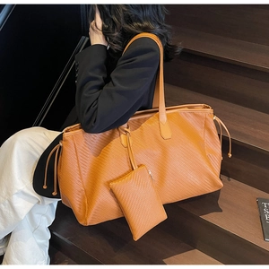 Détail d'un grand sac cabas en cuir tressé avec pochette assortie porté par un mannequin