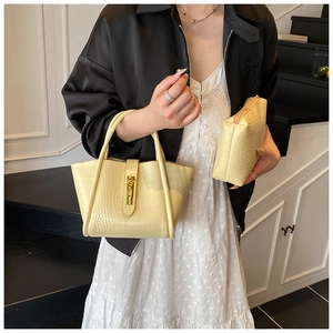 Detail of pale yellow crocodile texture bucket bag set with golden swivel lock