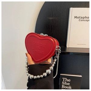 Detail of red heart-shaped mini bag with embossed text and silver bead handle chain