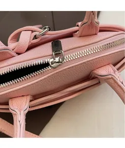 Gros plan d'un sac rose en cuir grainé avec fermeture éclair en métal argenté poli