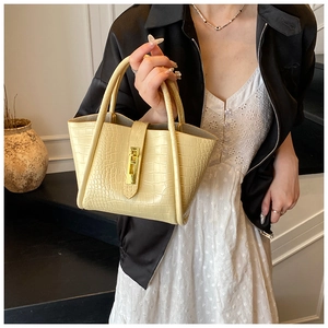 Detailed view of yellow crocodile embossed texture on bucket bag with gold buckle