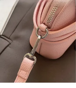 Détail de sac en cuir litchi rose avec crochet en métal argenté et fermeture éclair chic