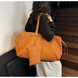 Vue détaillée d'un grand cabas tressé orange et sa pochette sur un escalier en bois