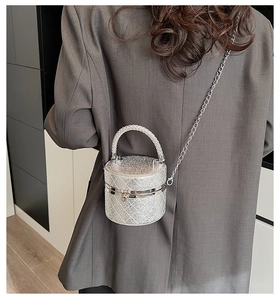 Makroansicht der silbernen Zylindertasche mit Glitzer-Steppmuster und Metallkette