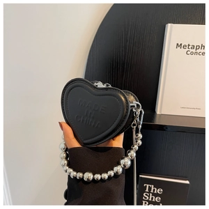 Detail of black heart-shaped mini bag with embossed lettering and silver bead chain