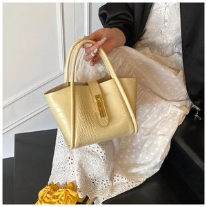 Detail of yellow crocodile embossed bucket bag with gold lock and leather strap